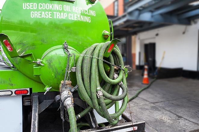 worker pumping grease trap at commercial kitchen in Brighton, MI