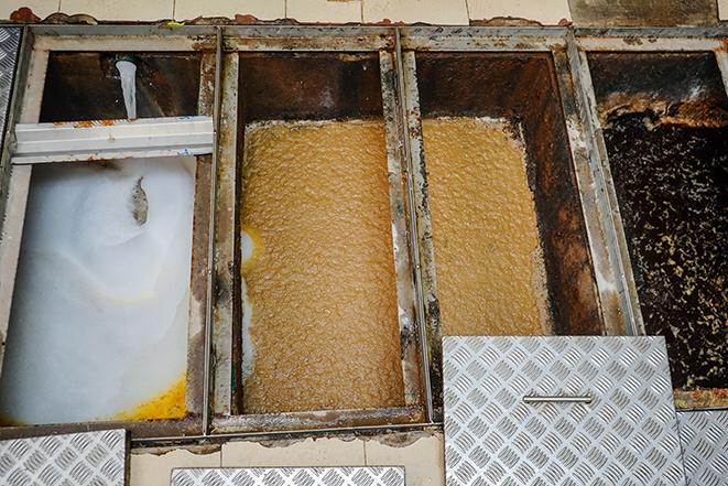 a kitchen grease trap being emptied and cleaned by a technician